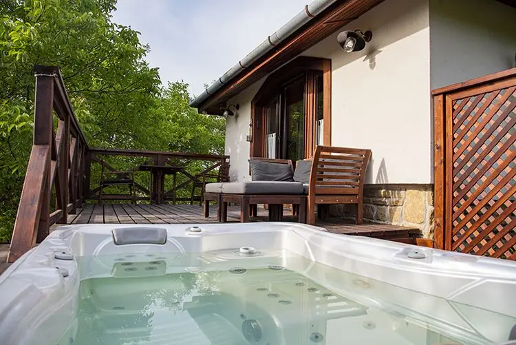 Jakuzzi a faburkolatú teraszon, erdővel körülvéve